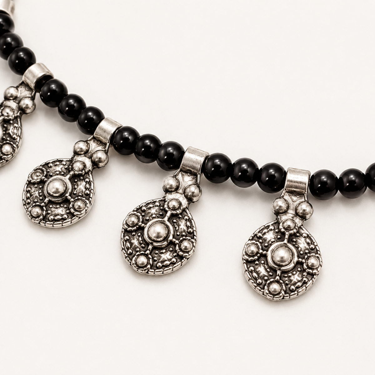 Close view of the filigree charm details and black beads.