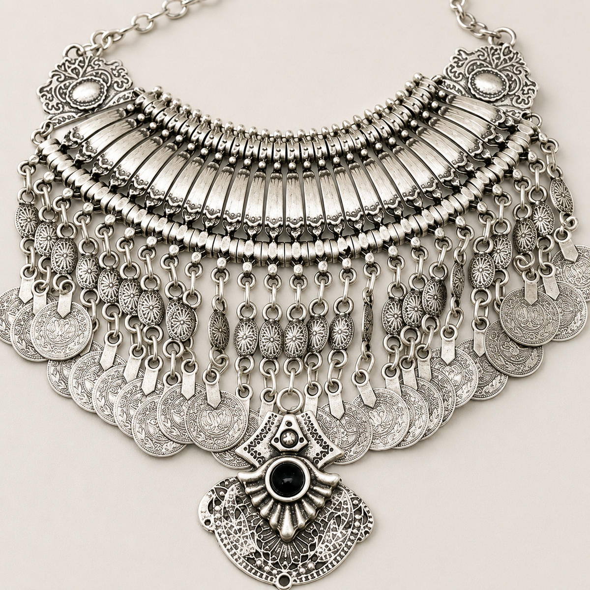 Close view of the textured silver-tone coins and black stone pendant.
