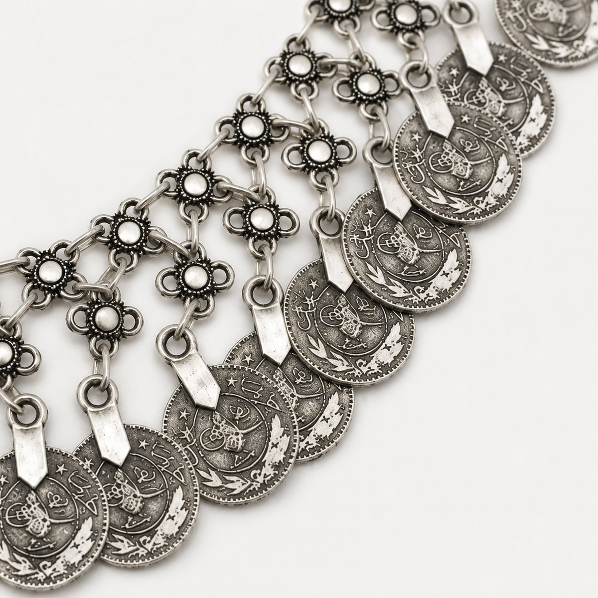 Close view of the floral links and engraved coin charms on the necklace.