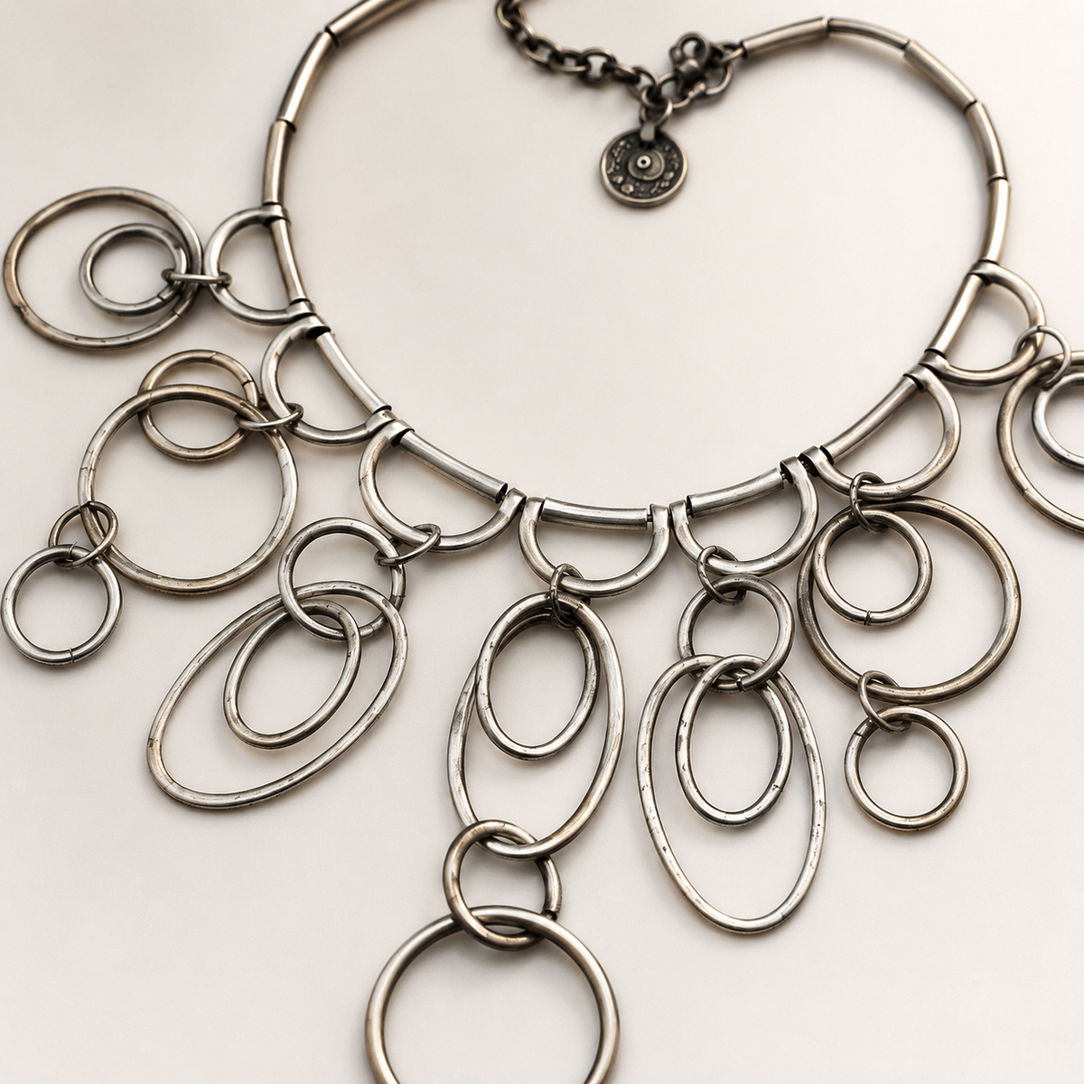 Close-up of the silver-tone ring drop necklace showing its linked circular details.