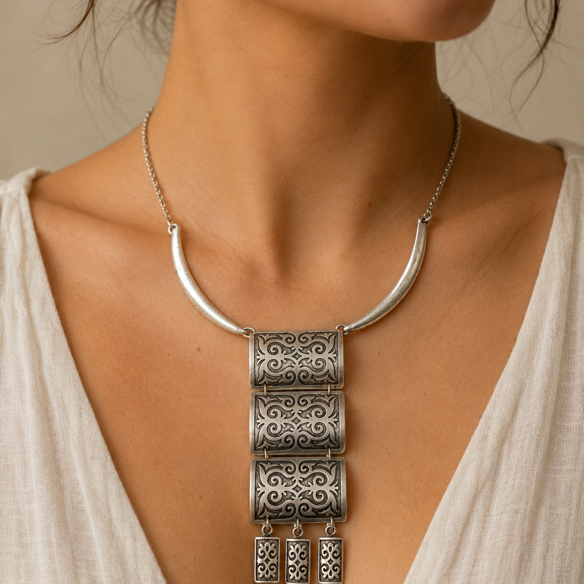 Silver-tone necklace with a stacked panel fringe pendant and curved chain.