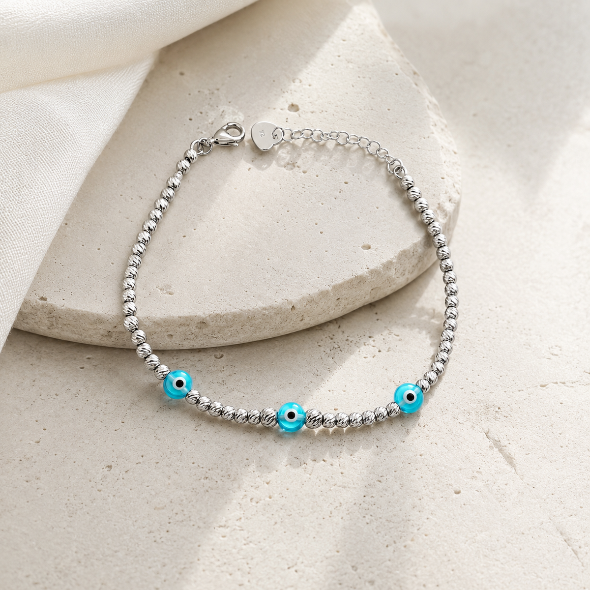 Silver-tone beaded bracelet with blue eye accents in a simple studio image.