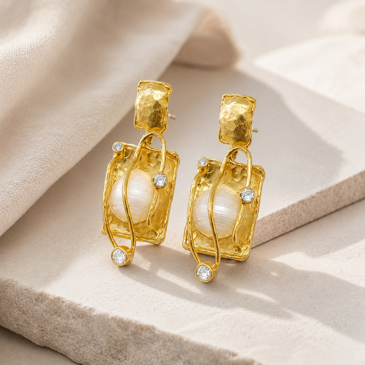 Angled view of pearl caged gold-plated earrings with clear accents.