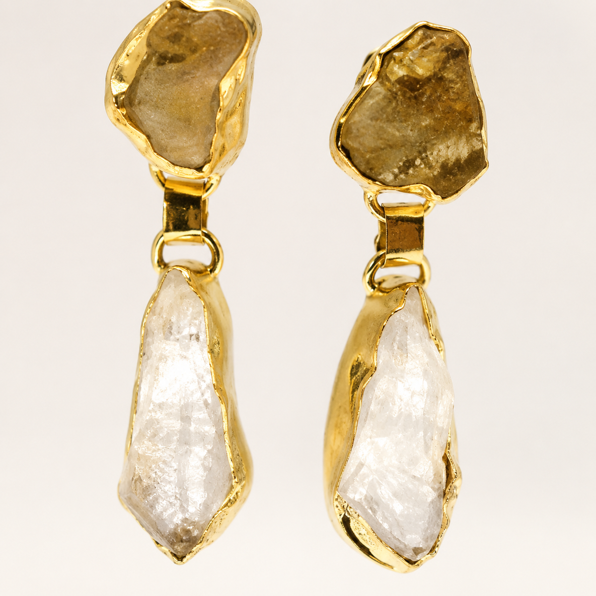 Close-up of rough citrine and clear quartz stones in a gold-plated setting.