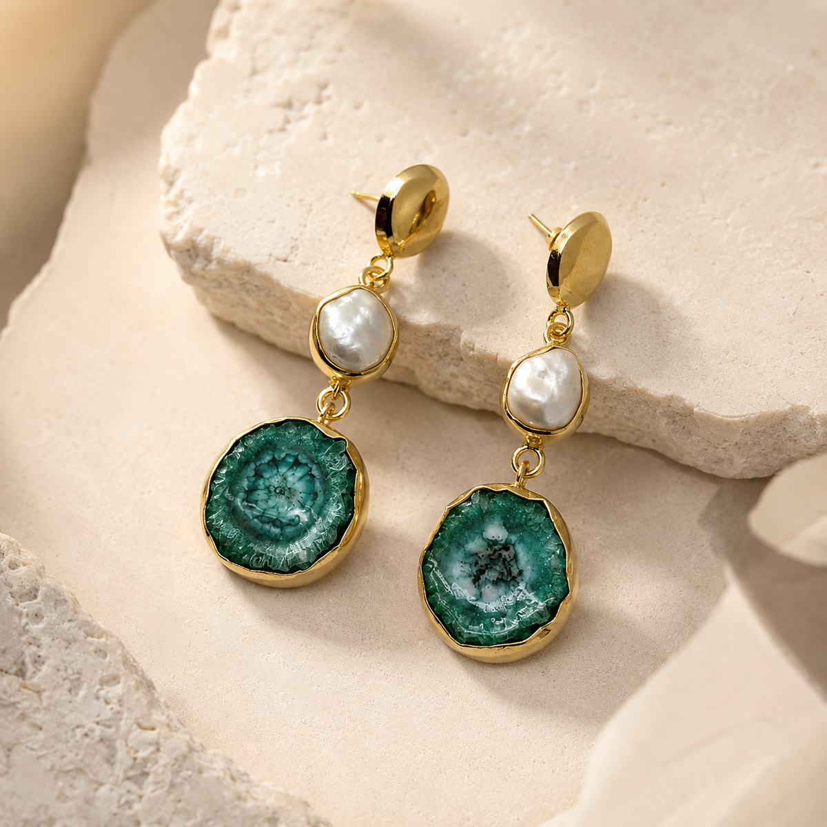 Side view of gold-plated drop earrings with a baroque pearl and green agate pendant.