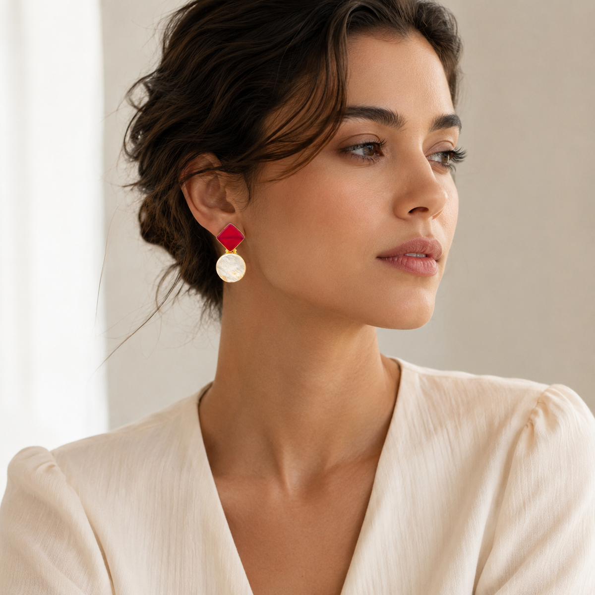 Front view of geometric drop earrings with red and clear stone-like elements.