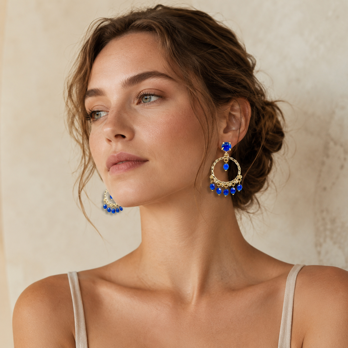 Front view of bold blue stone dangle earrings with a gold-plated finish.