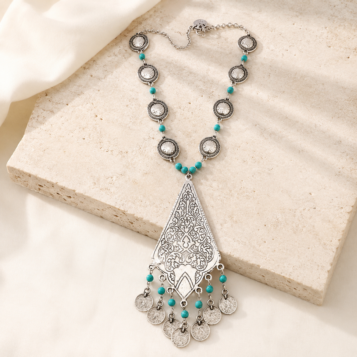 The necklace styled as a statement piece with turquoise accents and a teardrop pendant.