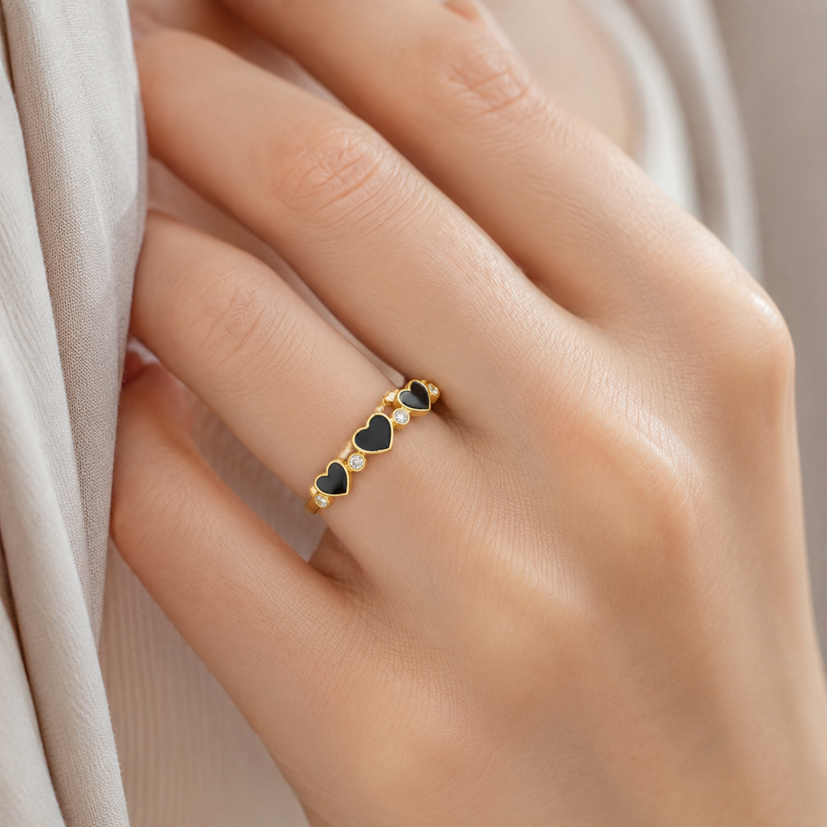 Gold-tone ring with black heart details and sparkling clear stones.