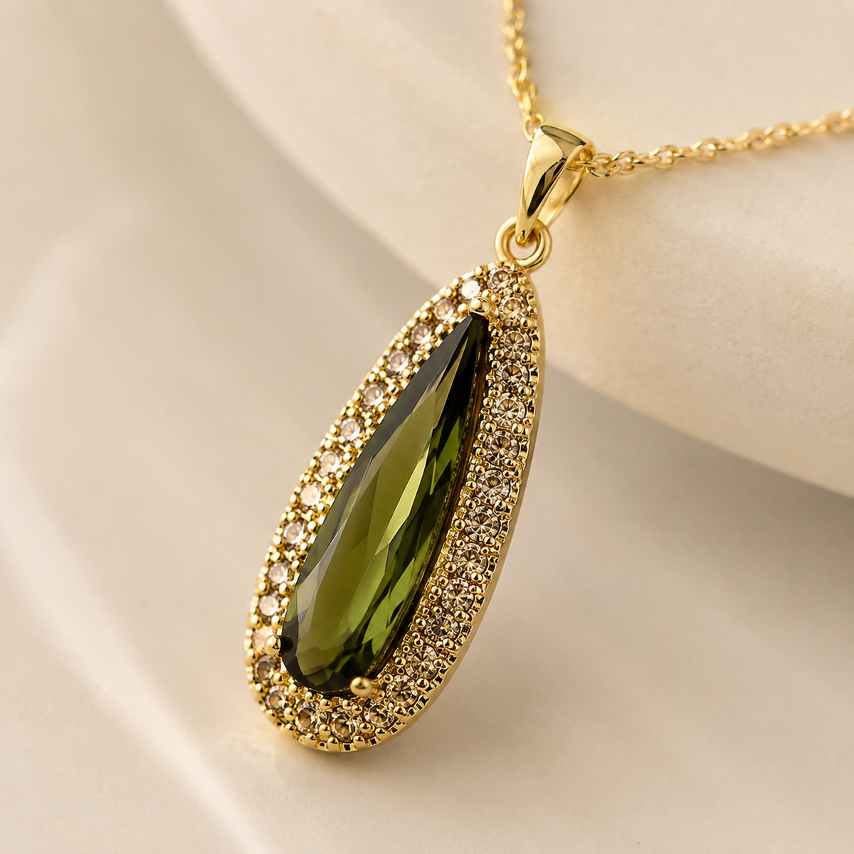 Close view of a teardrop pendant with green center and gold-tone frame.