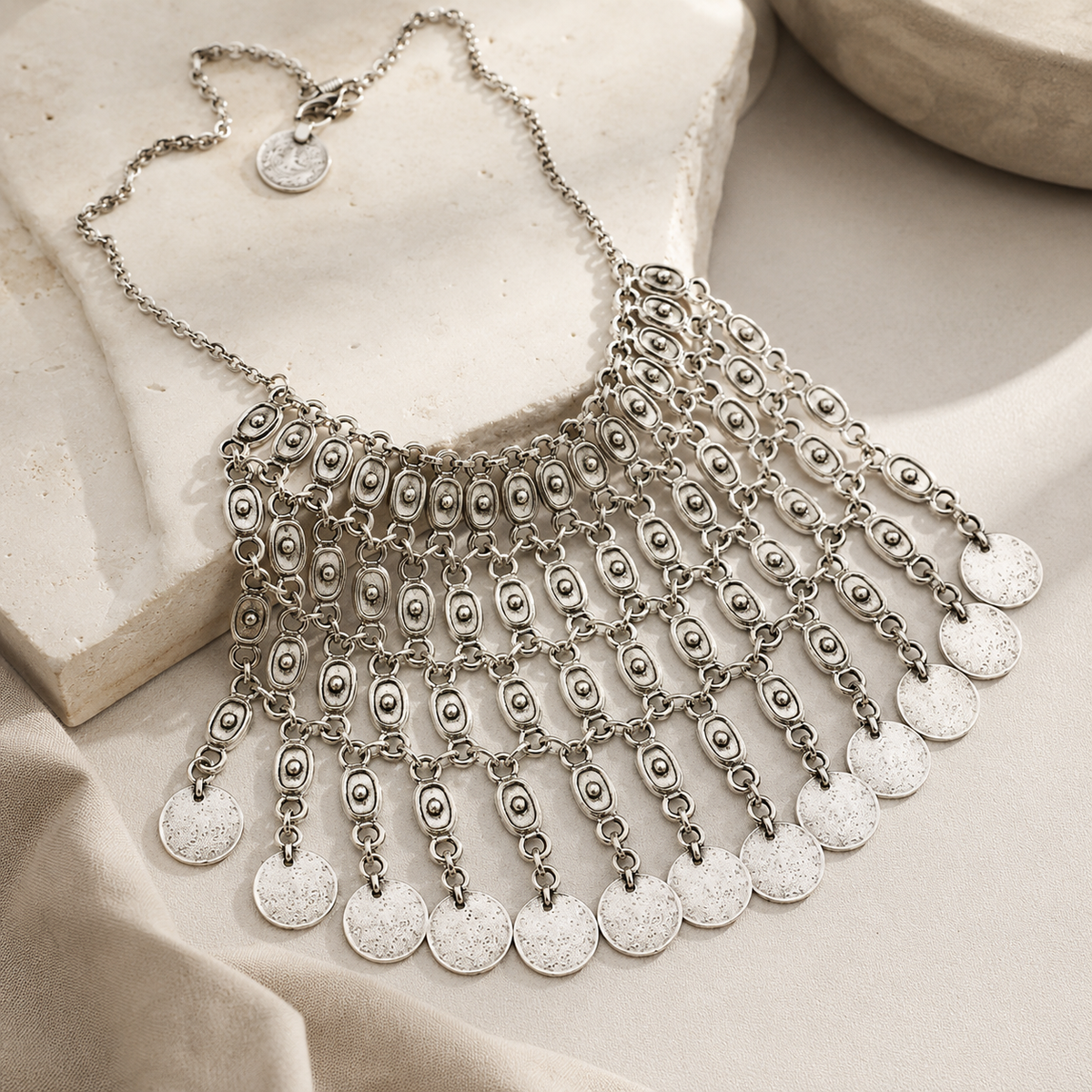 Angled view of the oval link necklace with coin fringe.