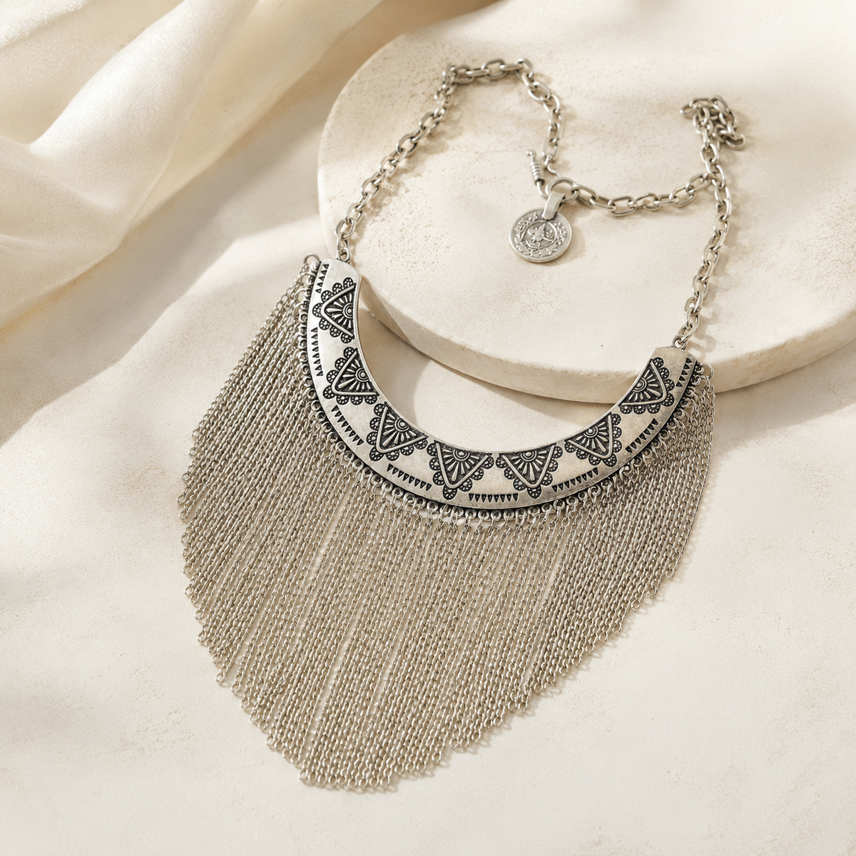 Silver-tone collar necklace with ornate engraving and long chain fringe.