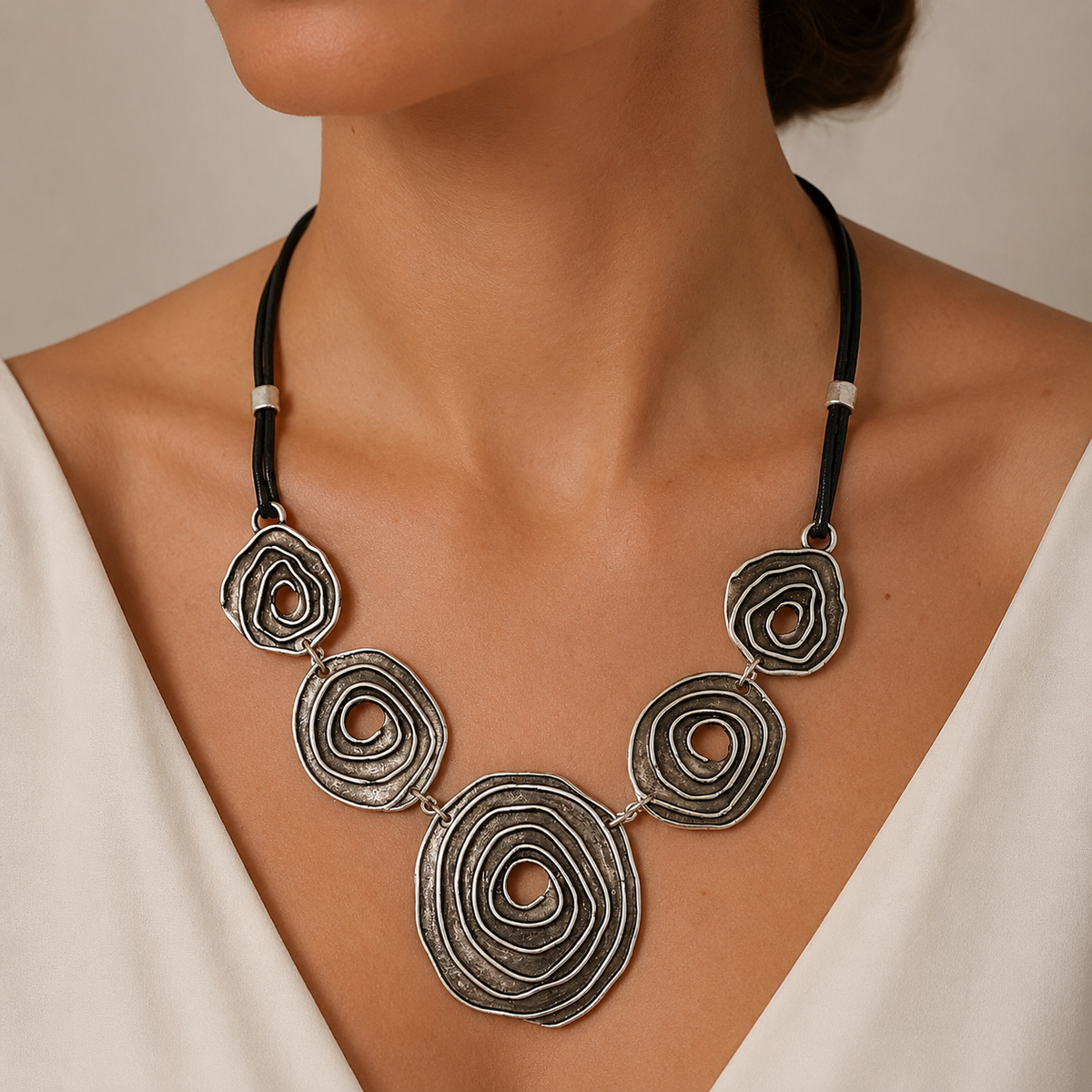 Black cord necklace with spiral circle pendants shown on a white background.