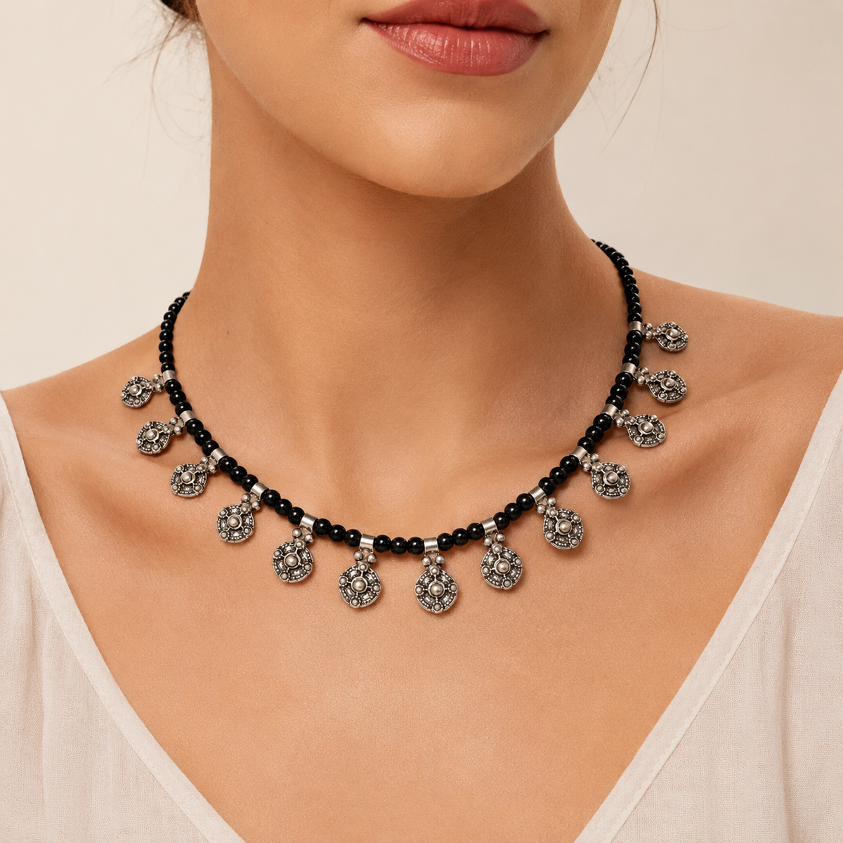 Black bead necklace with ornate silver-tone charms shown from the front.