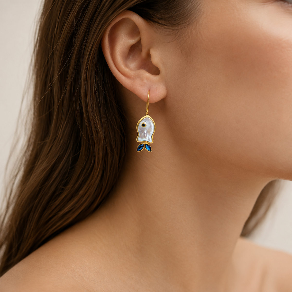 Gold-plated hook earrings with mother-of-pearl fish shapes and blue CZ accents.