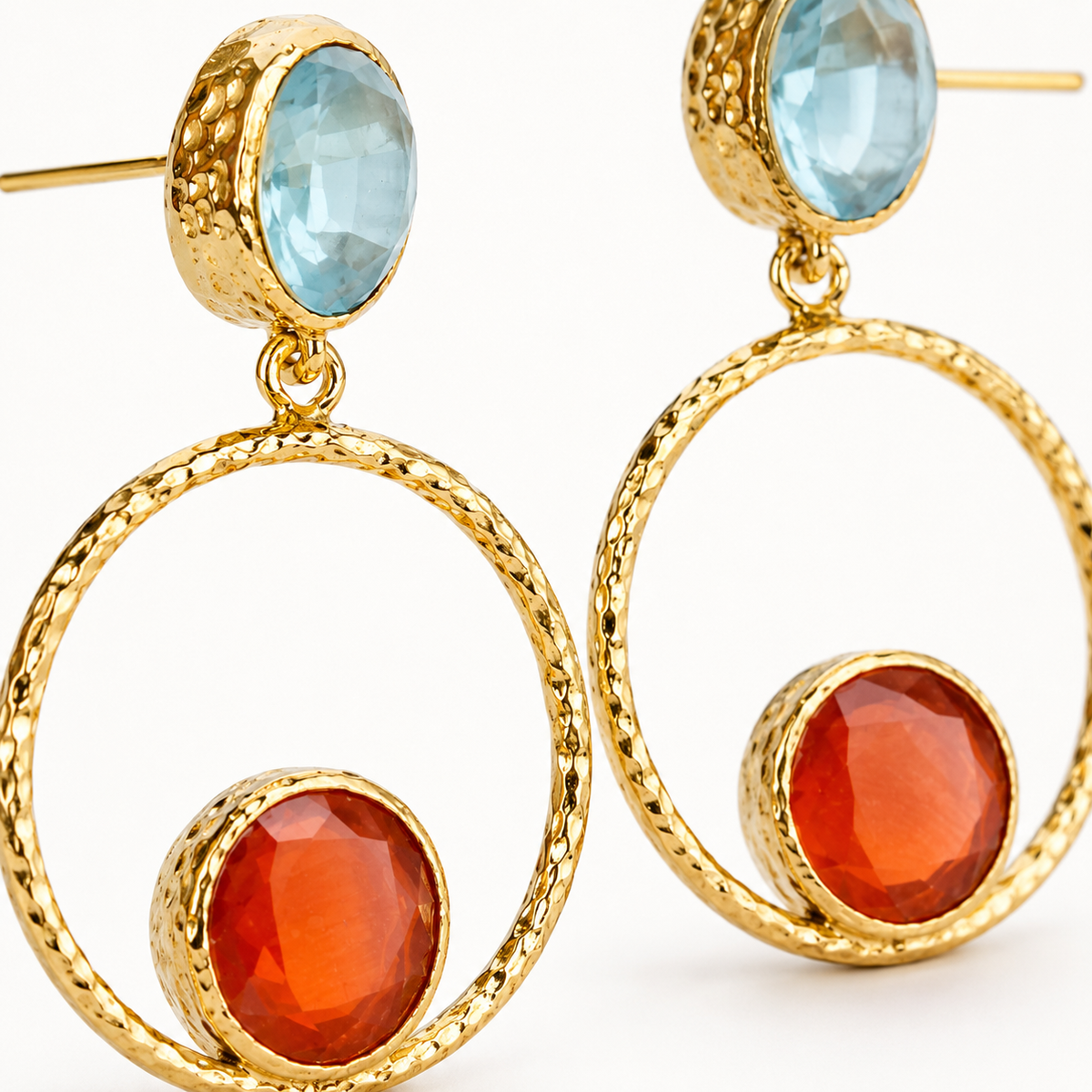 Close-up of a gold-plated earring with faceted teal and orange accents.