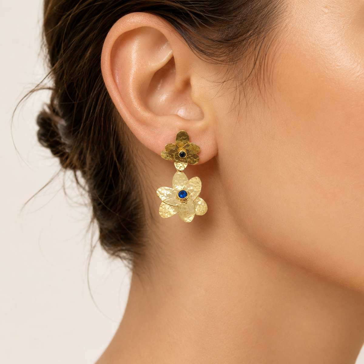 Gold-plated double flower drop earrings with blue stone centers shown front view.
