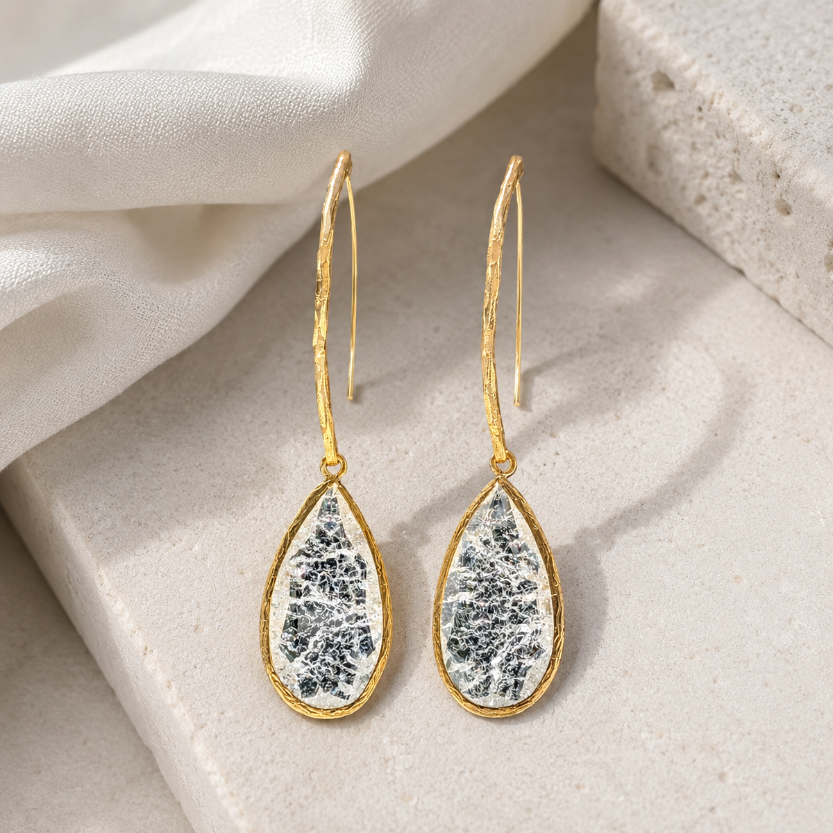 Teardrop drop earrings with a textured crystal-like center and gold-tone outline.