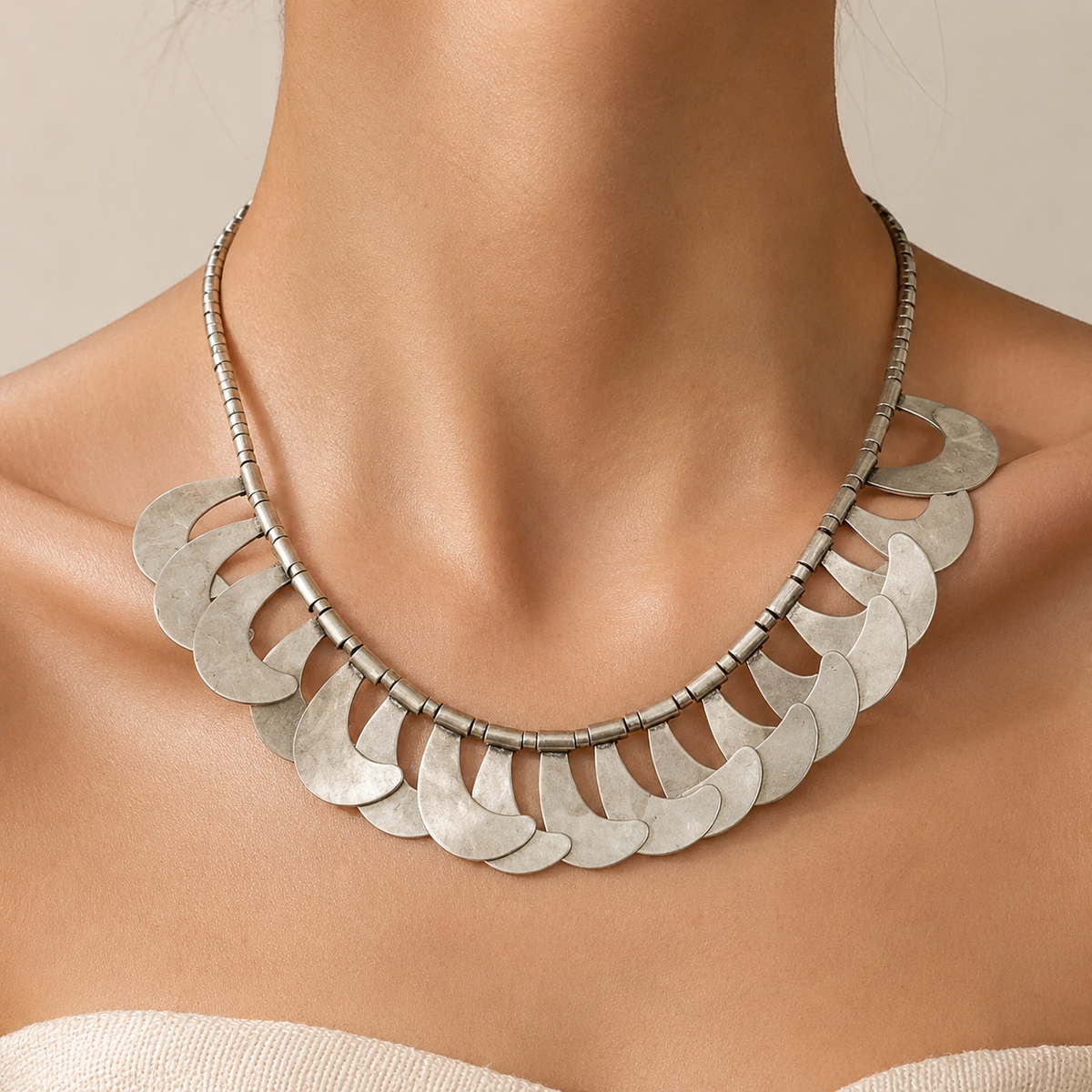 Silver-tone crescent scale collar necklace shown from above.