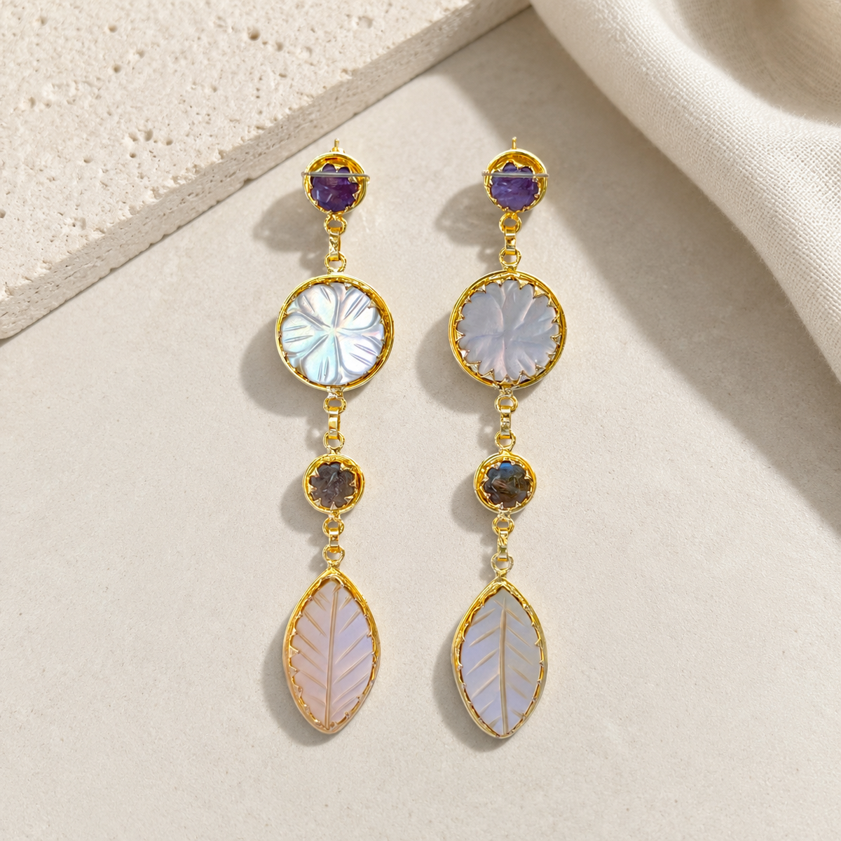 Gold-plated drop earrings with layered stone accents on a white background.