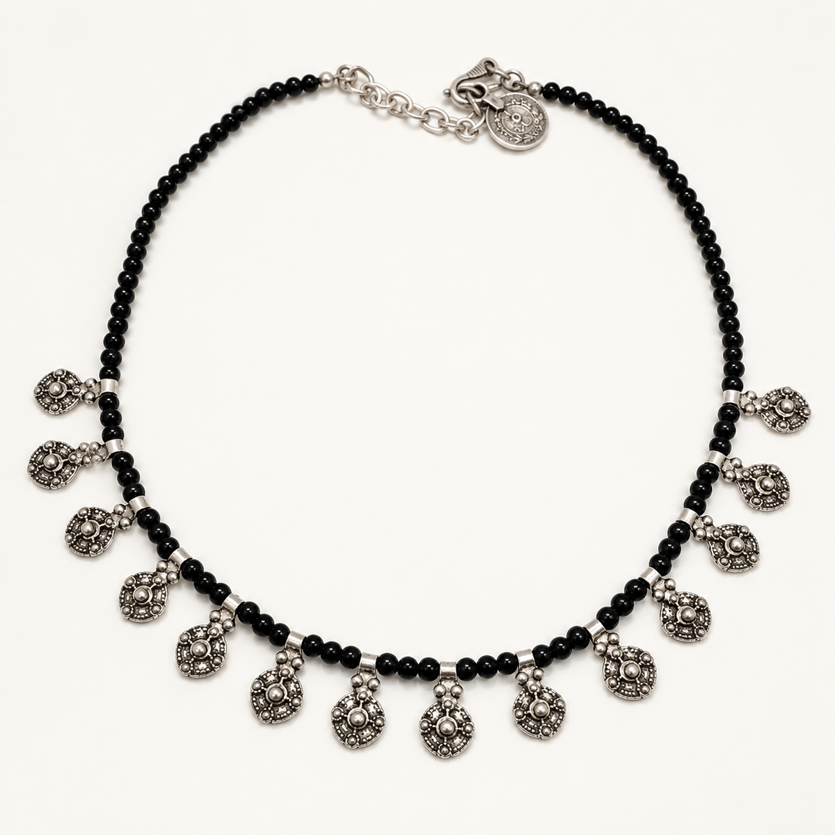 Black bead necklace with silver-tone filigree charm drops on a white background.