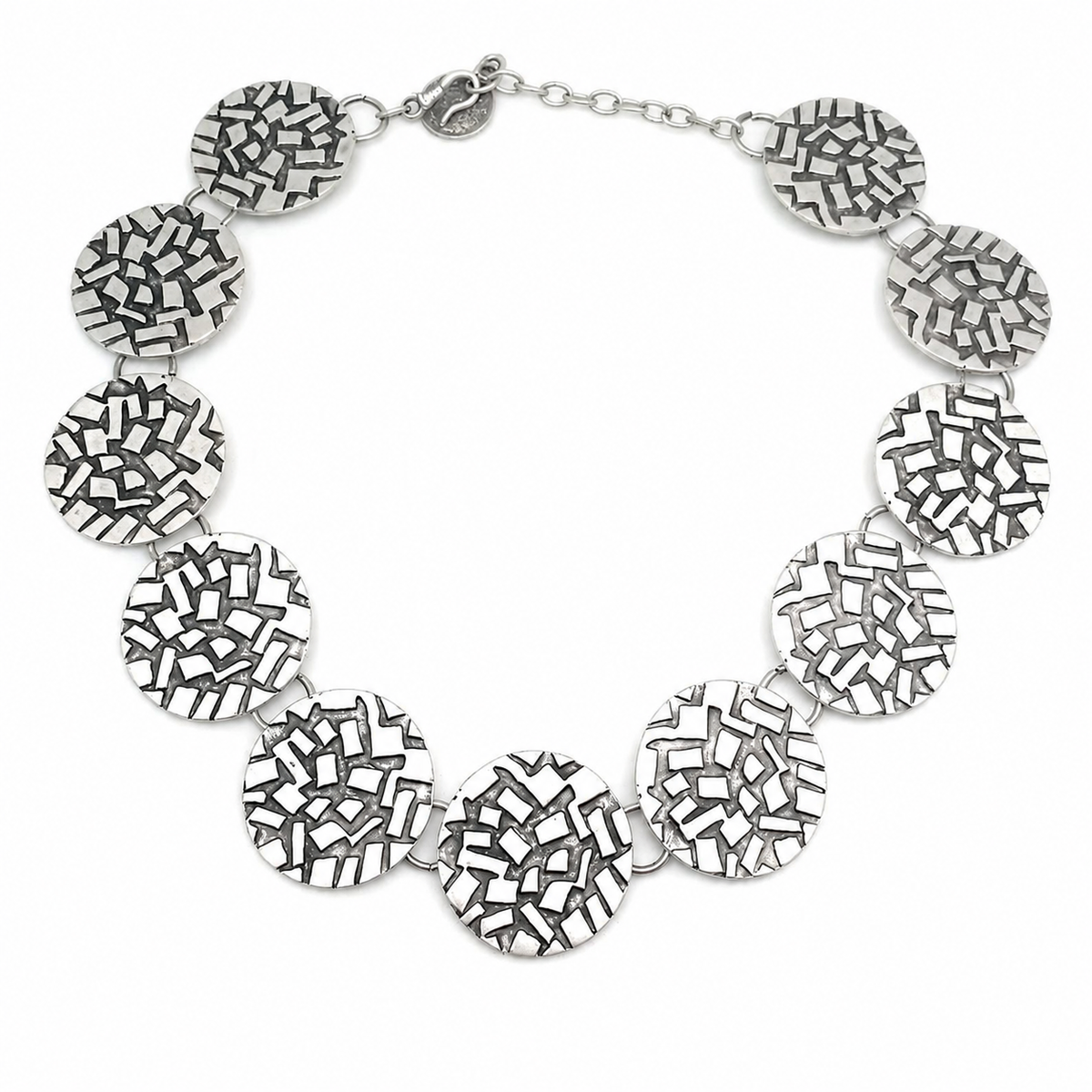 Silver round disc statement necklace with a textured mosaic-like surface.