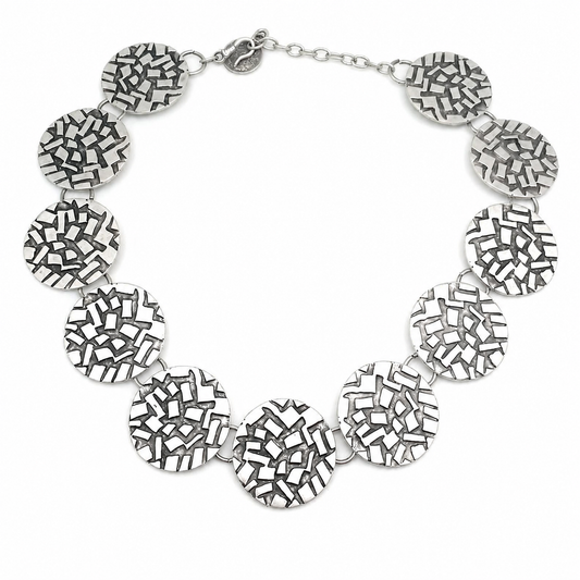 Silver round disc statement necklace with a textured mosaic-like surface.