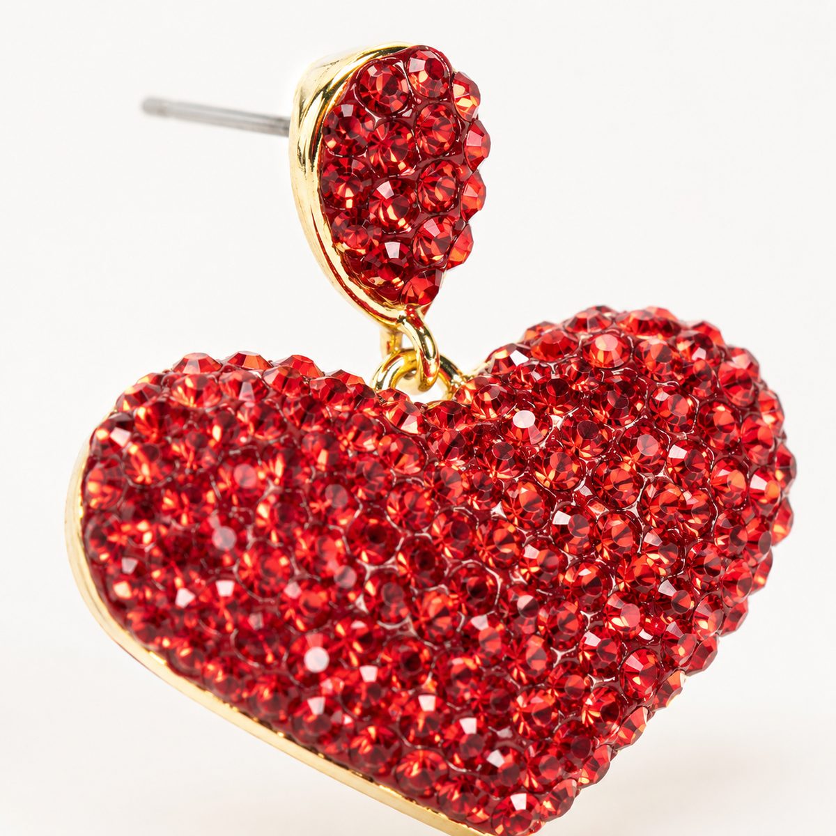 Close view of red crystal heart stud earrings with a gold-plated finish.