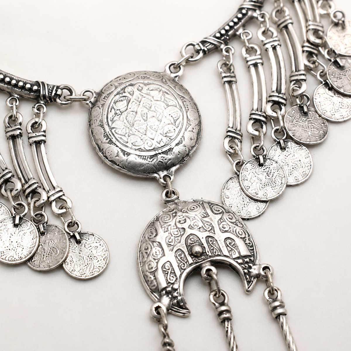 Close view of the etched coin and crescent details on the silver-tone necklace.