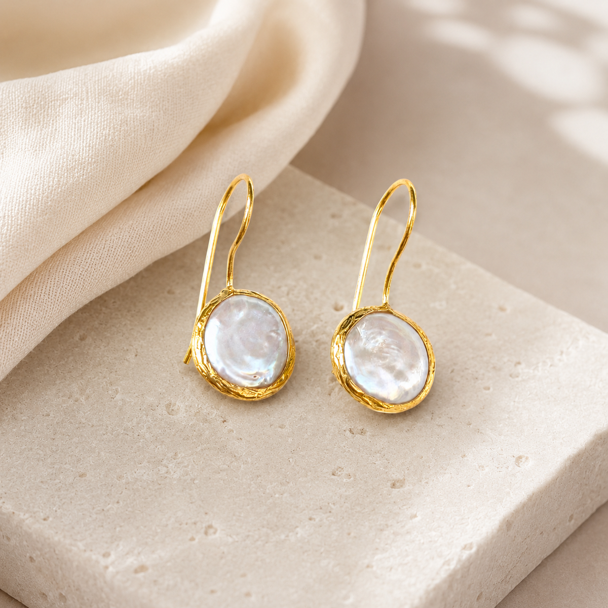 Gold-plated drop earrings with coin pearl centers in a clean studio view.