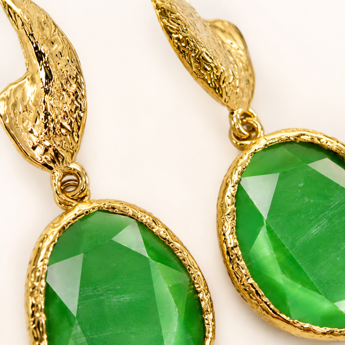Close view of the green faceted stone and textured gold-plated setting.