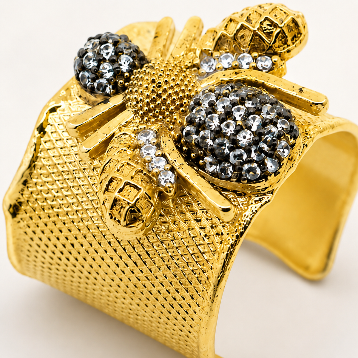 Close-up of a wide gold-plated ring with CZ accents and bee-inspired details.