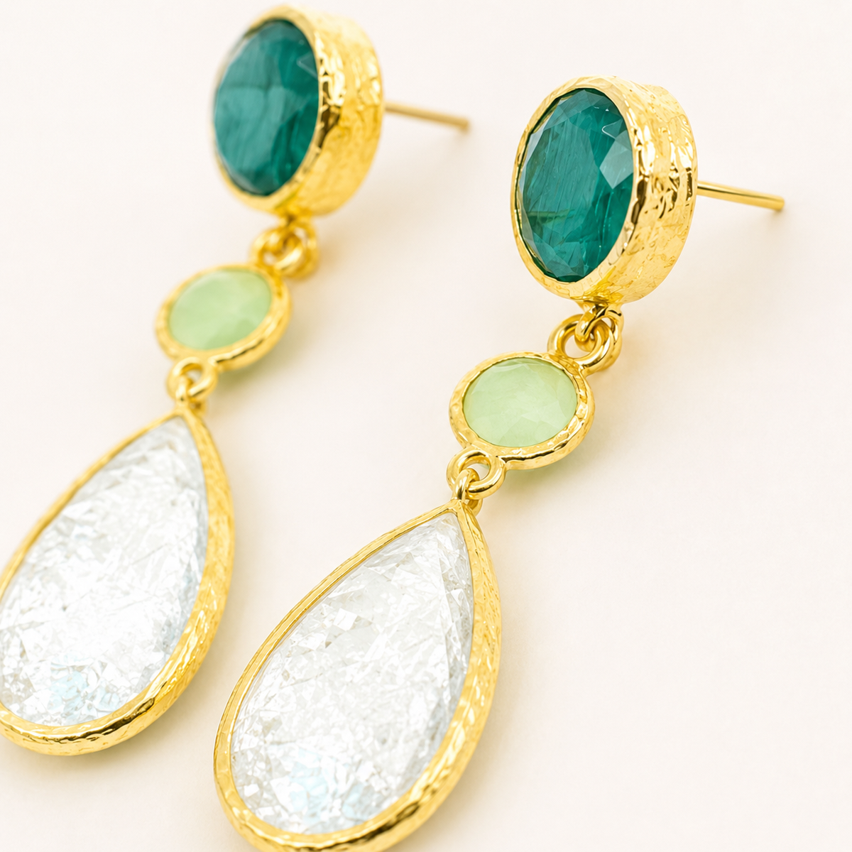 Close view of the faceted stone details on gold-plated dangle earrings.