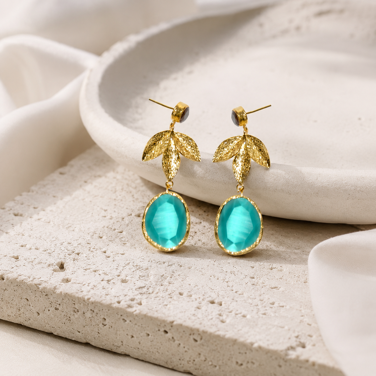 Gold-tone drop earrings with turquoise stones and leaf-shaped accents.