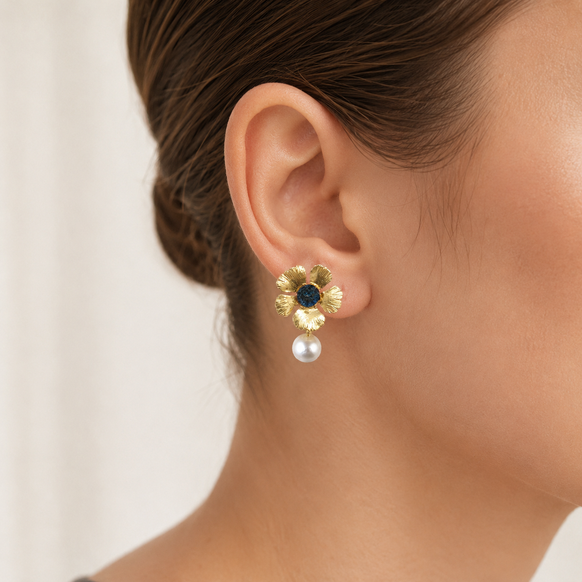 Gold flower drop earrings with a blue center and pearl drop.