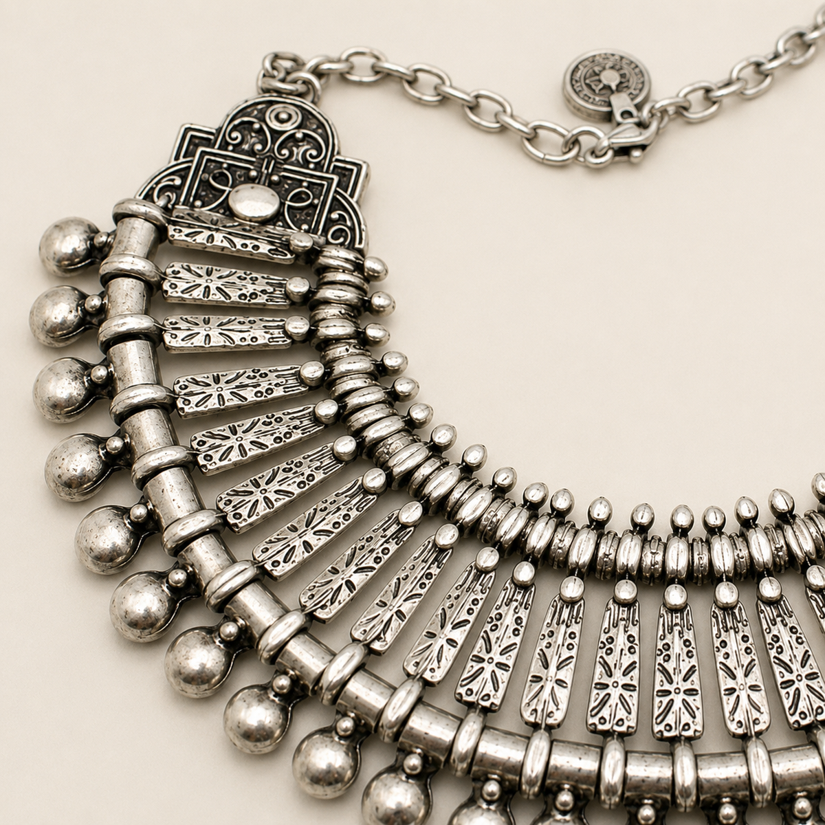 Close view of the ornate silver-tone fan necklace detailing and textured finish.