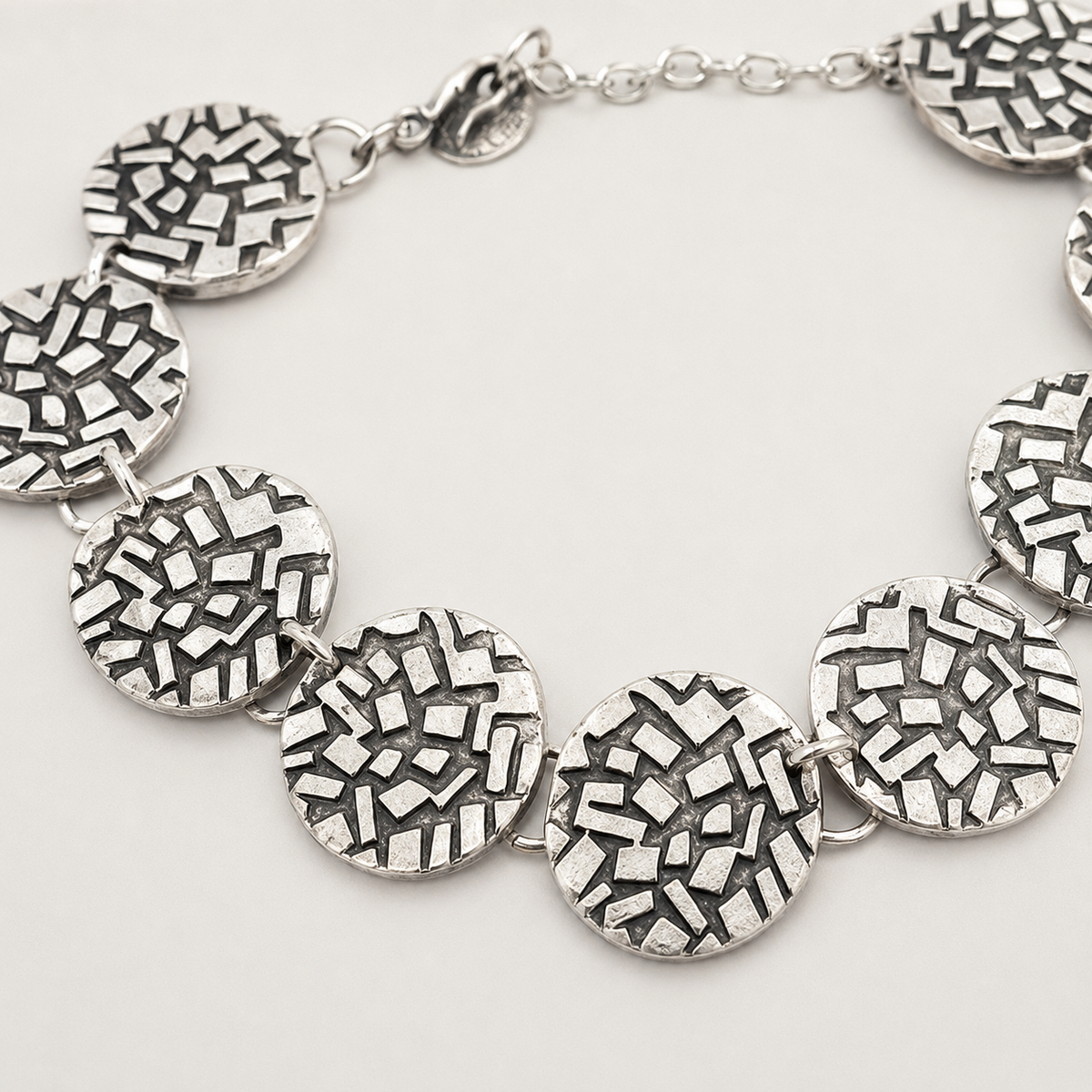 Close view of the textured round disc details in silver tone.