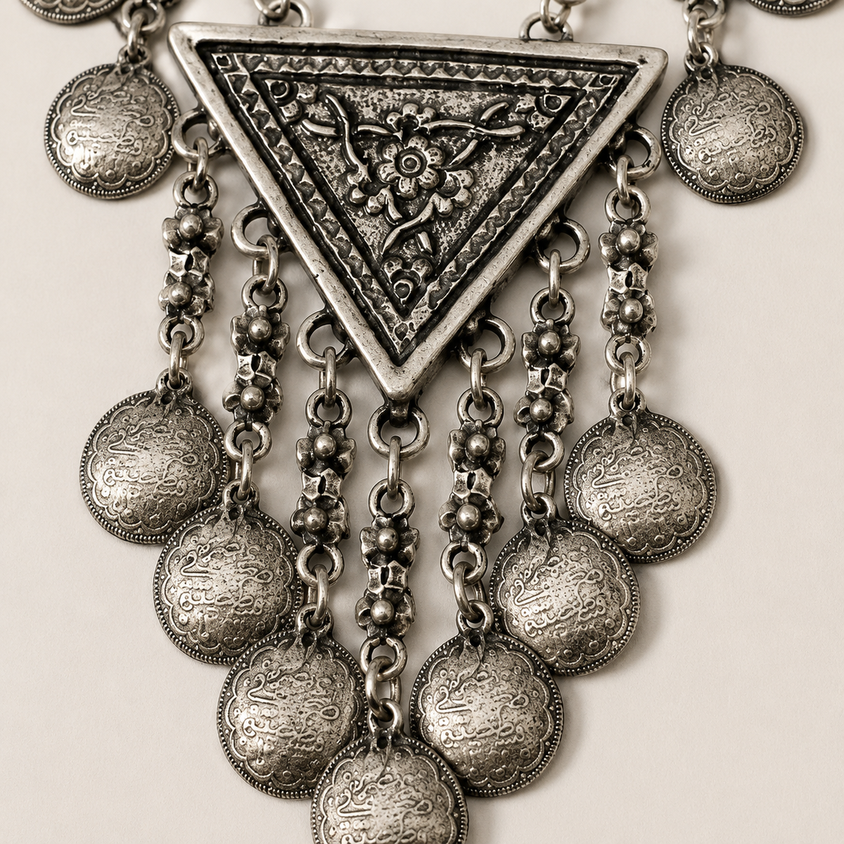 Close view of the textured silver-tone crescent pendant and coin details.