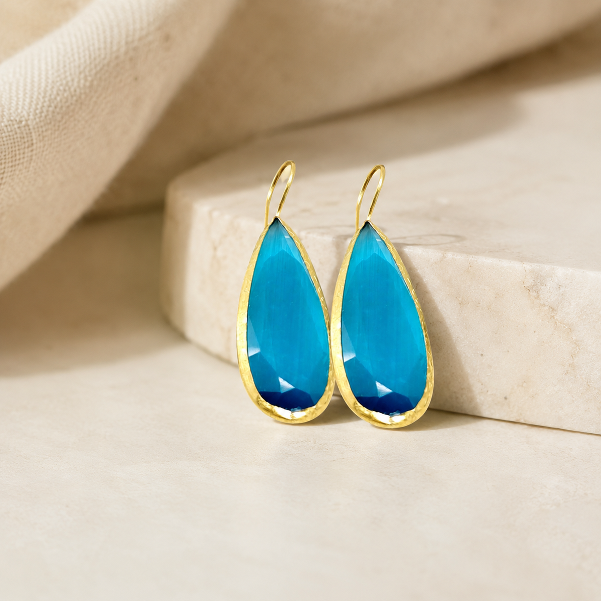 Teardrop drop earrings in ocean blue and gold-tone styling.