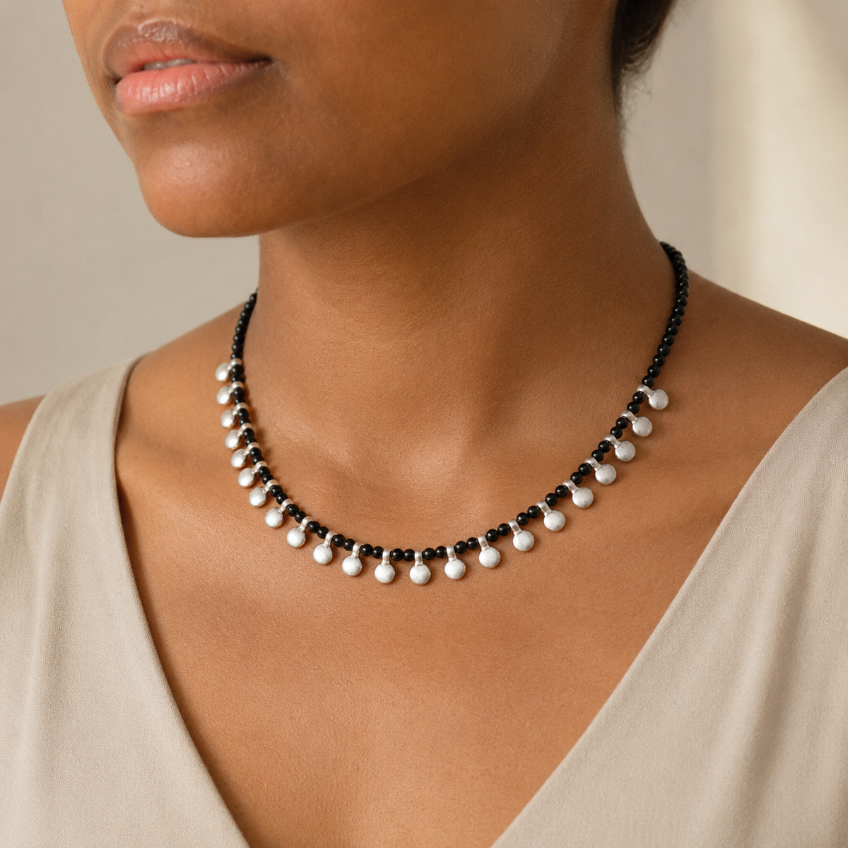 Black bead necklace with silver disc accents shown from the front.