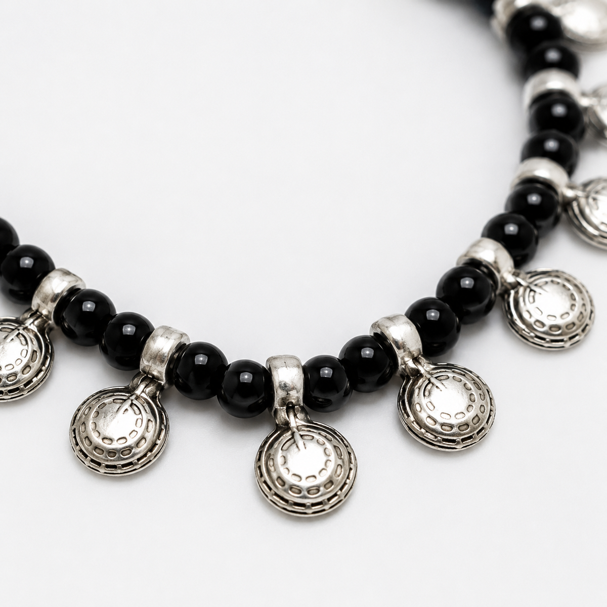 Close view of the black beads and round charm details.