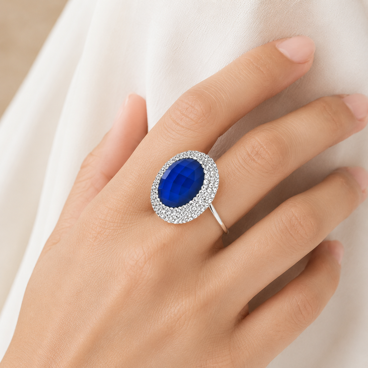 Blue stone ring shown at an angle with a bright halo of clear accents.