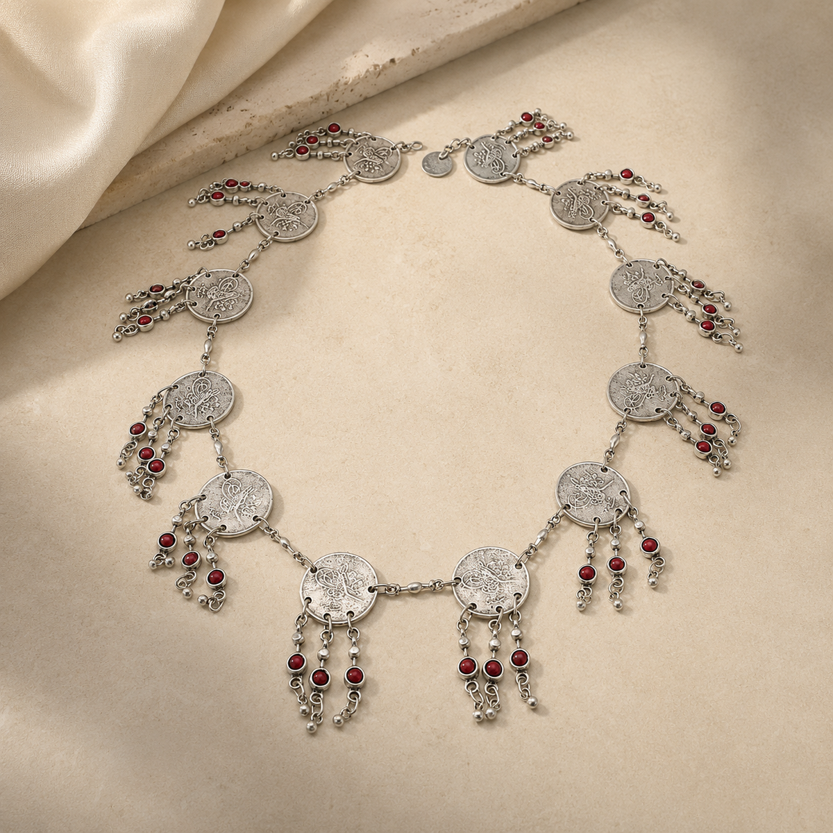Silver-tone necklace with layered coin charms and red bead fringe.