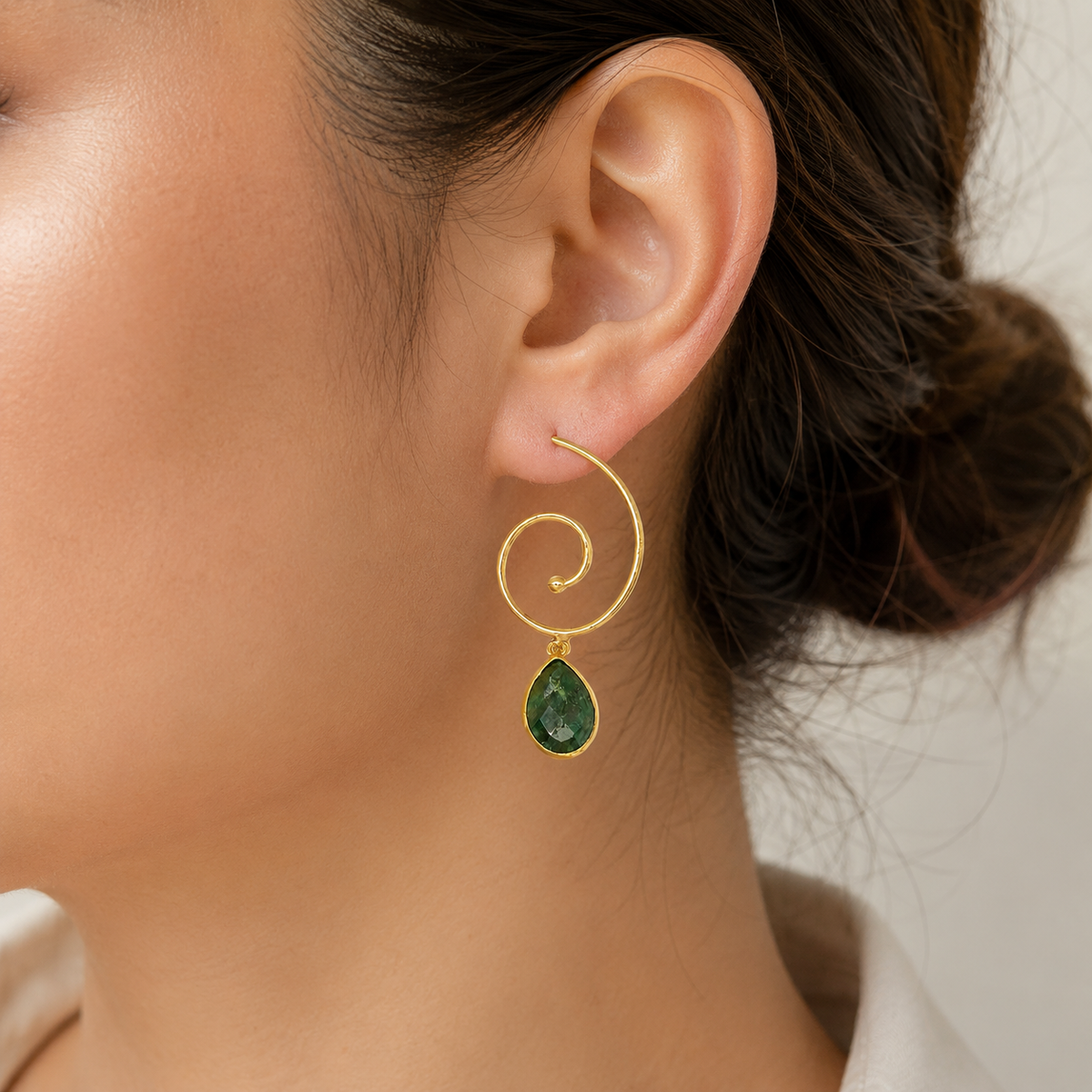 Gold-plated spiral drop earrings with green teardrop stones shown from the front.