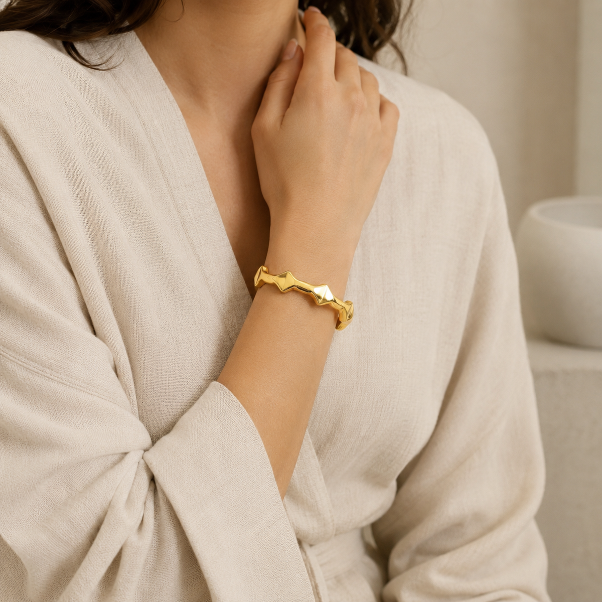A sculptural gold-tone cuff bracelet with a modern wave silhouette.