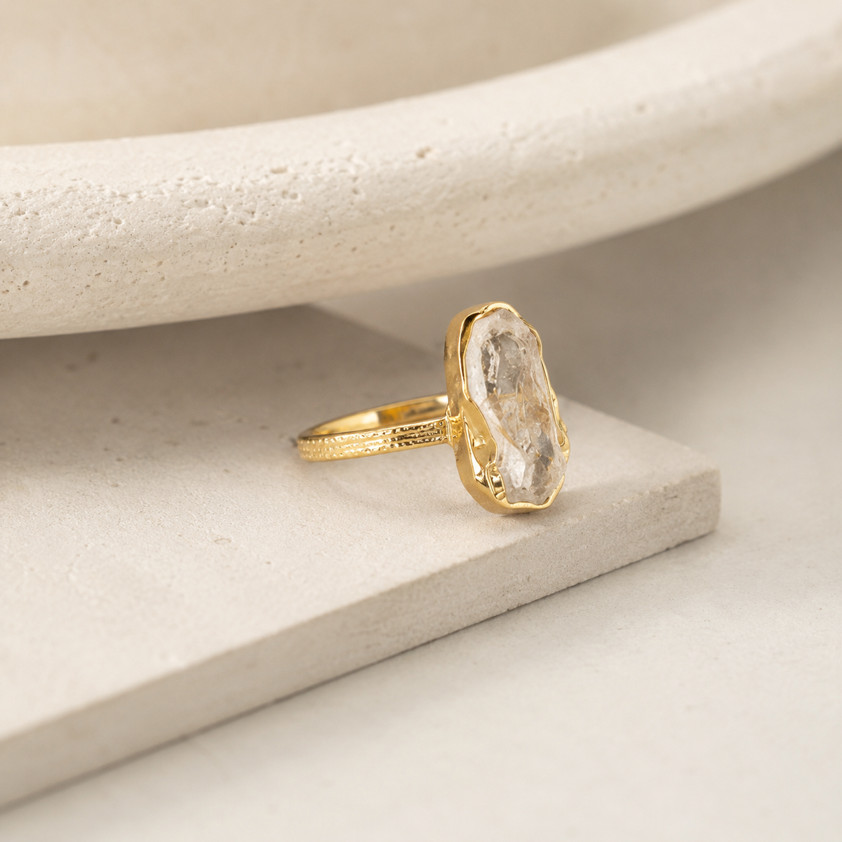Angled view of a raw clear quartz statement ring in gold plating.