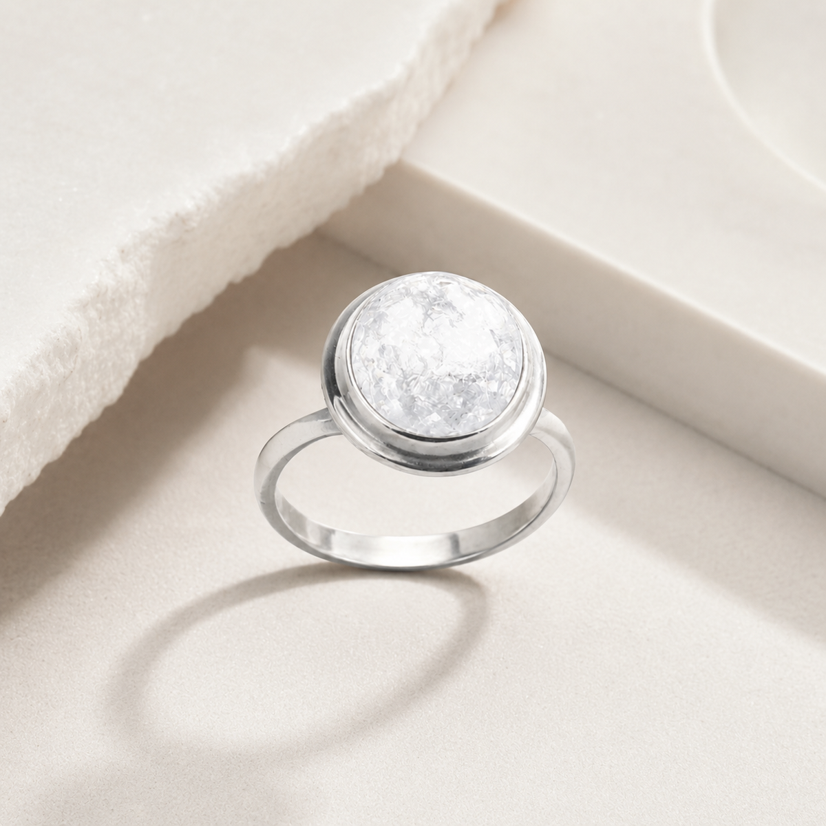 Angled view of a silver-tone bezel ring with a clear quartz-inspired center.