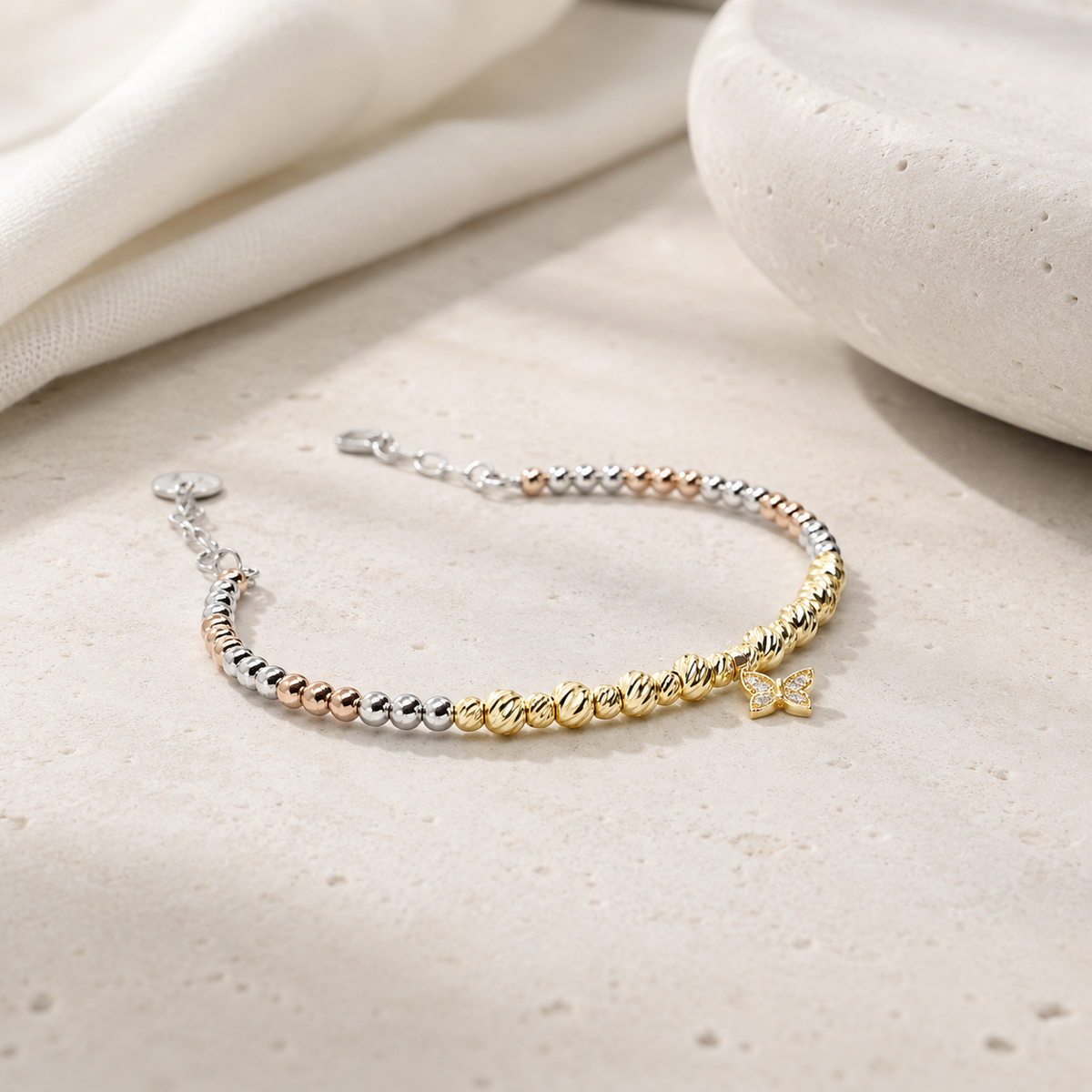 Bracelet with mixed metallic beads and a butterfly charm on a white background.