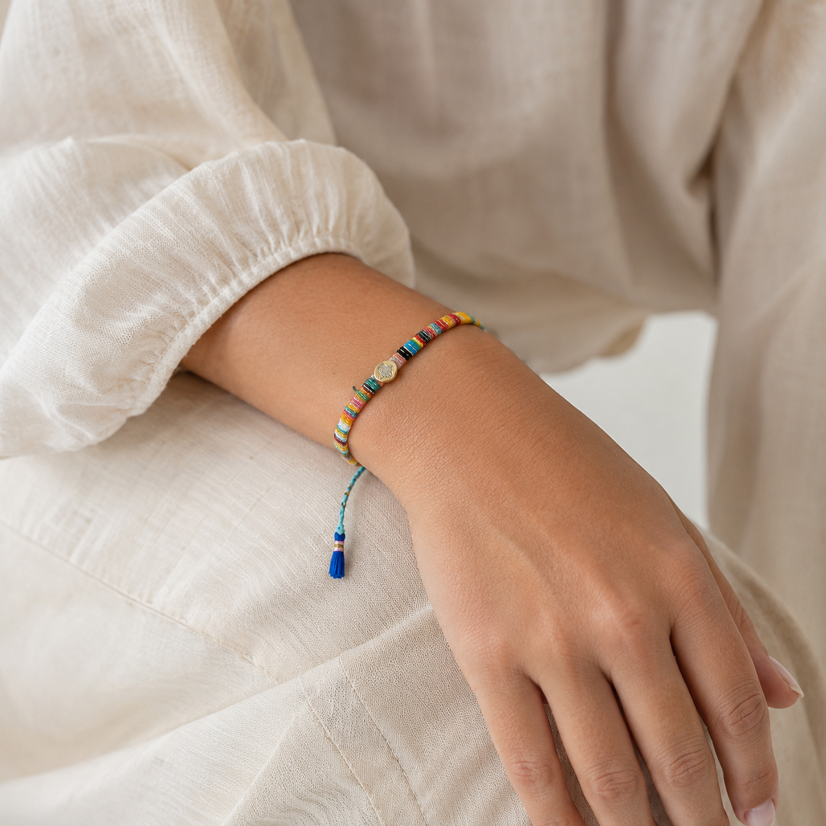 Colorful thread bracelet with gold-tone accents and a slim braided silhouette.