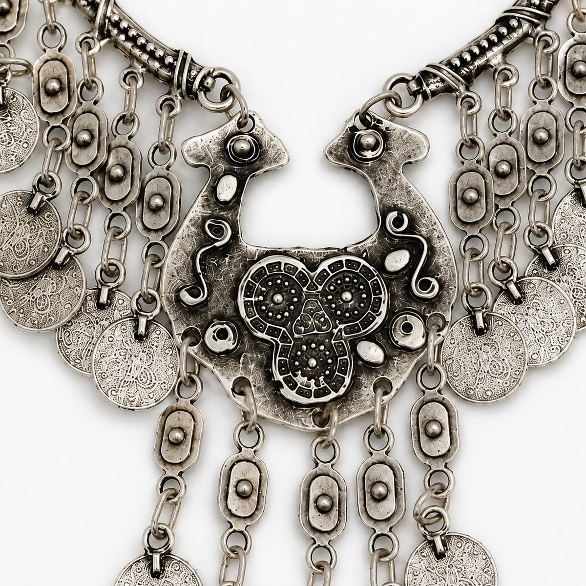 Close view of the necklace’s textured silver-tone centerpiece and fringe charms.